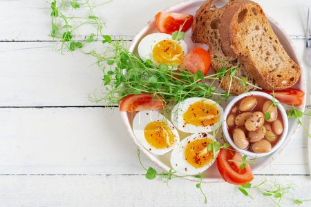 Foto de Desayuno inglés. Huevo cocido, frijoles, tostadas y hierbas verdes. Vista superior, plano - Imagen libre de derechos