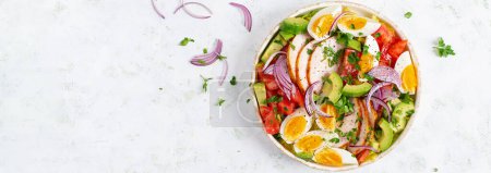 Healthy cobb salad with chicken, avocado, tomato, red onions and eggs. American food. Top view, banner