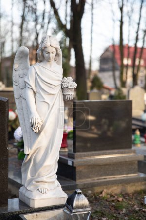 Foto de La escultura del Ángel Blanco en el Cementerio Mater Dolorosa en Bytom. El ángel sostiene las flores y mira hacia abajo. - Imagen libre de derechos