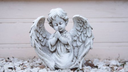 Foto de Antigua escultura destruida de un angelito blanco. Ángel con las manos dobladas en oración y los ojos cerrados. - Imagen libre de derechos