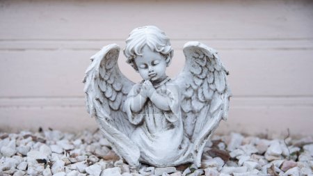Foto de Antigua escultura destruida de un angelito blanco. Ángel con las manos dobladas en oración y los ojos cerrados. - Imagen libre de derechos