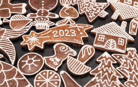 Photo for Beautiful gingerbread for happy New Year 2023 in Bethlehem star shape among ornate Xmas sweets. Close-up of baked aromatic handmade Christmas cookies decorated by white frosting on a black background. - Royalty Free Image