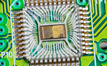 Photo for Closeup of electronic integrated circuit die with photodiode array and gold wires on a green PCB. Micro chip inside optical computer mouse image sensor in plastic package with round hole and metal pins. - Royalty Free Image