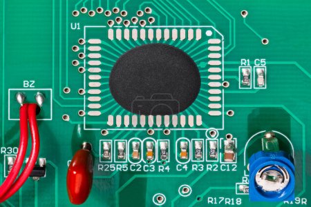 Chip-on-Board-Bestückung einer integrierten Schaltung auf einer grünen Texturplatine mit roten Drähten. Nahaufnahme eines direkt gebundenen Mikrochips in Epoxid-Tropfen und elektronischen Bauteilen wie Potentiometer, Widerstände oder Kondensatoren.