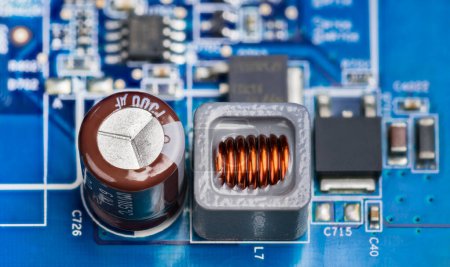 Photo for Close-up of electronic components on printed circuit board of a power supply. Brown electrolytic capacitor, inductor in gray housing and black transistors or micro chip on a blue PCB. Electrotechnology. - Royalty Free Image