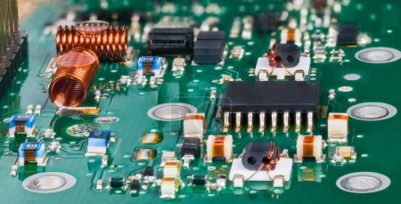 Photo for Closeup of surface mounted electronic components in radio-frequency circuits of a TV tuner. Semiconductor microchip and air core coils with various small inductors, capacitors or resistors on green PCB. - Royalty Free Image