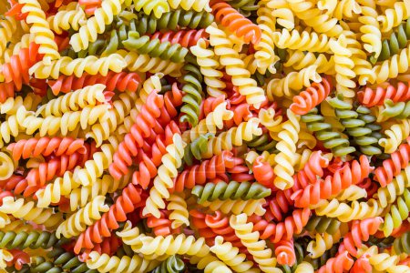 Photo for Closeup of three color fusilli variety pasta in beautiful colorful texture. Culinary background from many raw dried rotini yellow and red or green colored with tomato or spinach flavor. Italy cuisine. - Royalty Free Image