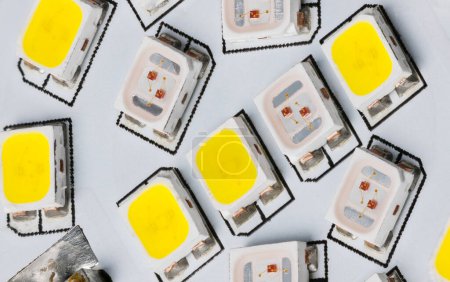 Closeup of light-emitting diodes on electronic LED circuit inside a household lamp. Electric light sources of yellow and white color temperature on printed wiring board detail. Surface mount assembly.