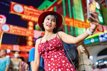 Foto de Night photo of thai woman taking selfie at Yaowarat Chinatown in bangkok thailand during chinese new year celebrations - Imagen libre de derechos
