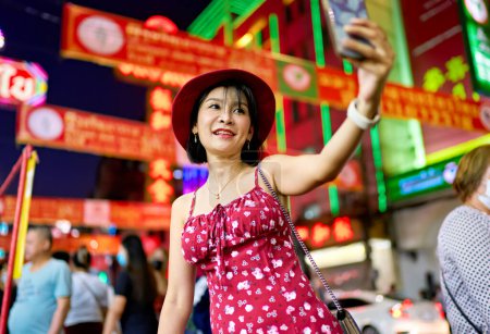 Photo for Night photo of thai woman taking selfie at Yaowarat Chinatown in bangkok thailand during chinese new year celebrations - Royalty Free Image