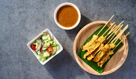 Foto de Thai satay skewers with grilled pork and dipping sauces served on banana leaf plate - Imagen libre de derechos
