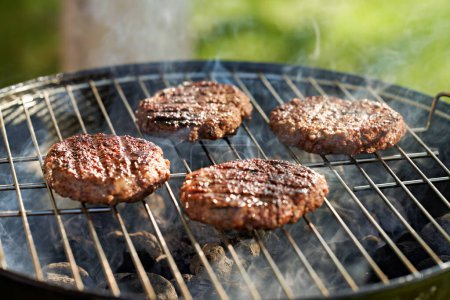 Photo for Hamburger patties being grilled on charcoal kettle grill - Royalty Free Image