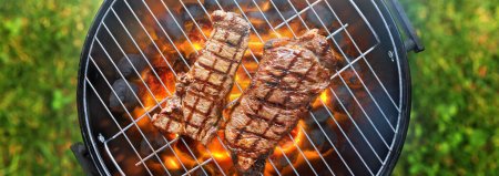 Photo for Grilling steaks on charcoal bbq grill outdoors in yard shot from top view - Royalty Free Image