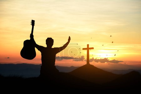 Téléchargez les photos : Homme debout tenant la croix chrétienne pour adorer Dieu au coucher du soleil. concept de silhouette chrétienne. - en image libre de droit
