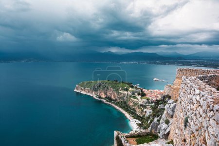 Vista desde Palamidi en la ciudad de Nafplio en Grecia con puerto, fortaleza de Bourtzi, y mar Mediterráneo azul. Día nublado.