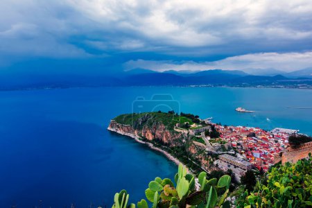 View from Palamidi on Nafplio city in Greece with port, Bourtzi fortress, and blue Mediterranean sea. Cloudy day.