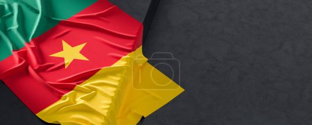 Flag of Cameroon. Fabric textured Cameroon flag isolated on dark background. 3D illustration
