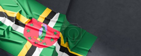 Flag of Dominica. Fabric textured Dominica flag isolated on dark background. 3D illustration