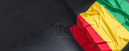 Flag of Guinea. Fabric textured Guinea flag isolated on dark background. 3D illustration