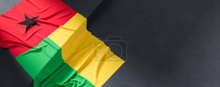 Flag of Guinea Bissau. Fabric textured Guinea Bissau flag isolated on dark background. 3D illustration