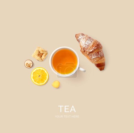 Creative layout made of tea, croissant and lemon on the beige background. Flat lay. Food concept.