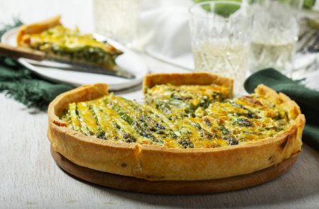 Tart stuffed with asparagus, spinach, chard, cream and cheese, served with white wine. Rustic style, selective focus.