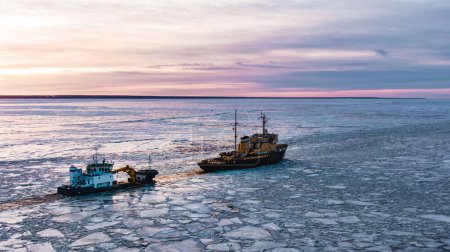 Téléchargez les photos : Le brise-glace va sur la mer parmi les glaces bleues au coucher du soleil, vue aérienne - en image libre de droit