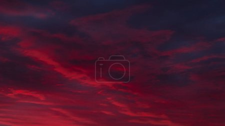 Der Himmel steht in feurigen roten und violetten Tönen in Flammen und schafft eine dramatische und atemberaubende Leinwand für den Sonnenuntergang. Dramatische rote und lila Sonnenuntergangswolken am dunklen Himmel 