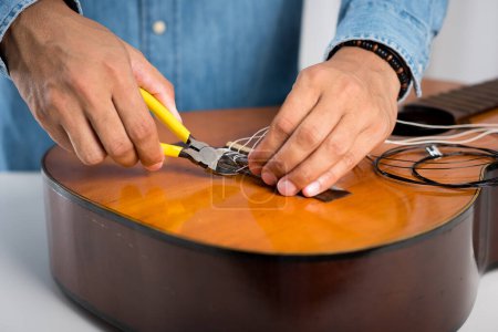 Photo for Restring classical guitar concept. The man restring his classical guitar. - Royalty Free Image