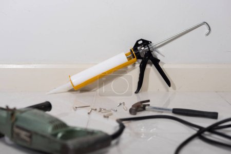Téléchargez les photos : White silicone sealant cartridge and yellow-black sealant gun - en image libre de droit