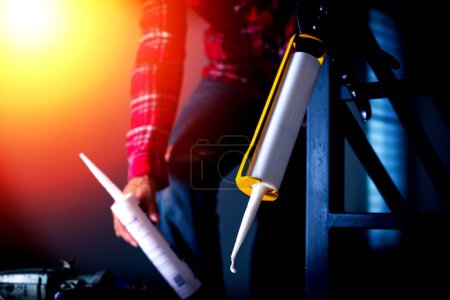 Téléchargez les photos : The man applying silicone caulk. The man fixing home. - en image libre de droit