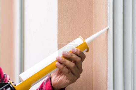 Téléchargez les photos : The man applying silicone sealant. The man fixing home. - en image libre de droit