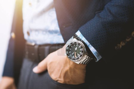 Téléchargez les photos : Closeup luxury men watch with black dial and stainless steel bracelet on wrist of man. - en image libre de droit