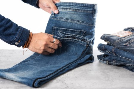 Photo for Closeup blue jeans in man hand over white background. - Royalty Free Image