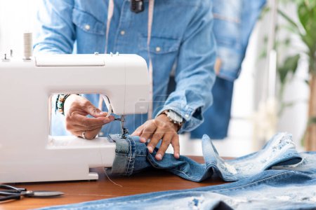 Photo for Tailor working with blue denim jeans. Tailor hem the blue jeans. - Royalty Free Image