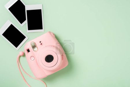 Foto de La cámara instantánea rosa con películas instantáneas en blanco sobre fondo verde. - Imagen libre de derechos