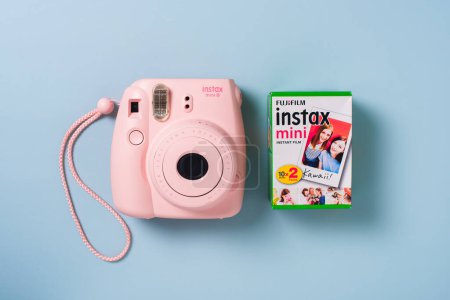 Foto de BANGKOK, TAILANDIA - 09 DE OCTUBRE DE 2019: La cámara instantánea rosa Fujifilm Instax mini 8 y un paquete de película instantánea sobre fondo azul. - Imagen libre de derechos