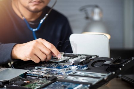 Computer service and repair concept. Technician using stethoscope with broken computer.