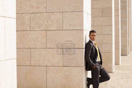 Triste homme d'affaires à côté d'un mur regardant vers le bas
