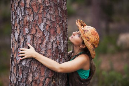 Young woman enjoying nature, embracing a tree trunk