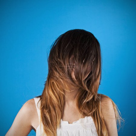 Frau mit Haaren über dem Gesicht vor blauem Hintergrund