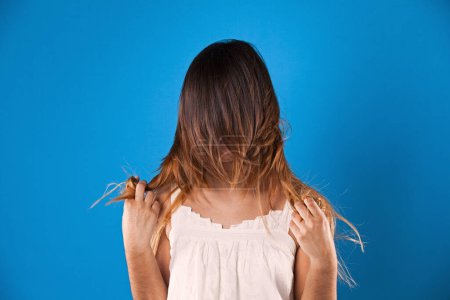 Woman with hair over her face in a blue background