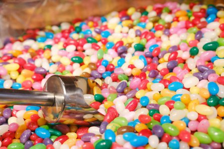 Mixed multi-colored jelly beans and a metal scoop in a candy store.