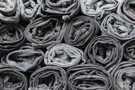 Photo for Lots of folded black and gray jeans. Denim background. Fashion denim clothing, shopping, fashion, consumption. - Royalty Free Image