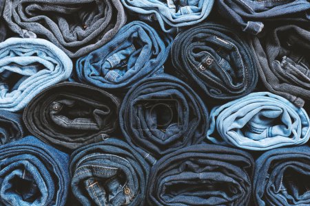 Photo for Lots of rolled up jeans. Denim background. Trendy denim clothing, shopping, fashion, consumption. - Royalty Free Image