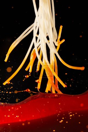 Photo for Close-up of jumping rice noodles with red chili oil and soup - Royalty Free Image