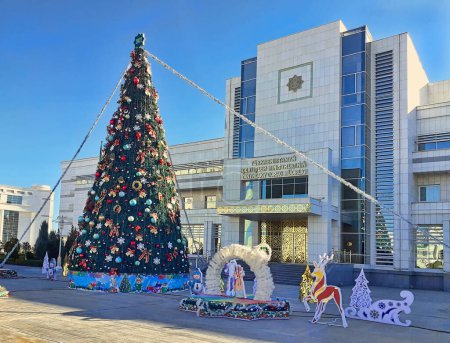 Téléchargez les photos : Ashgabat, Turkmenistan - January 07, 2022: Christmas tree on street of Ashgabat,  in the background the Ministry of Defense under the Ministry of Internal Affairs. - en image libre de droit
