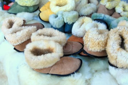 Téléchargez les photos : Chaussons en peau de mouton faits à la main. Pantoufles sont sur peau de mouton dans la boutique de cadeaux. - en image libre de droit