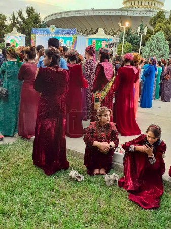 Téléchargez les photos : Achgabat, Turkménistan - 25 mai 2022 : Deux filles inconnues en vêtements nationaux regardent le téléphone. - en image libre de droit