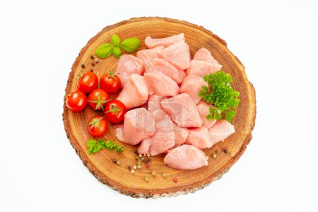 Fresh pieces of turkey meat.Raw chicken.Raw pieces of turkey meat with greens and tomatoes on a wooden board against a white background.Ogranic food and healthy eating.chicken fillet.